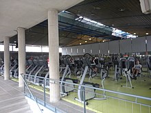[1] Ein großer Raum eines Fitnesscenters mit unterschiedlichen Geräten zum Trainieren