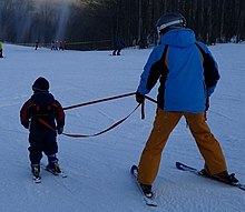 [1] ein Kind beim Skifahren an der Leine