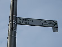 [1] Der Wegweiser zeigt die Richtung an, mit dem man mit dem Fahrrad 11,3 km bis nach Glücksburg fährt.