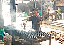 [1] Mann beim Grillen von Fisch (in Jakarta, Indonesien)