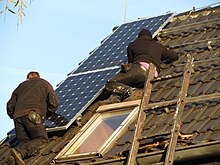 [1] Auf einem Dach werden Solarpanels installiert.