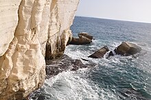 [1] unmittelbar vor einem Kliff aus dem Mittelmeer ragende Klippen bei Rosh haNikra (Nordisrael)