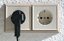 [1] zwei Steckdosen, links mit eingestecktem Stecker