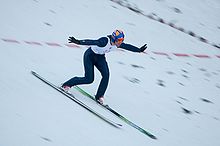 [1] ein Skispringer bei der Landung mit einem Telemark